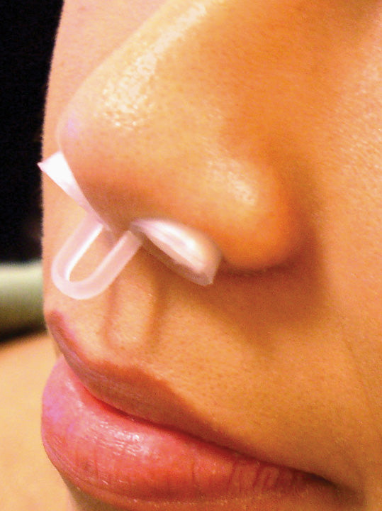 Close-up of a person using a nasal strip on their nose.