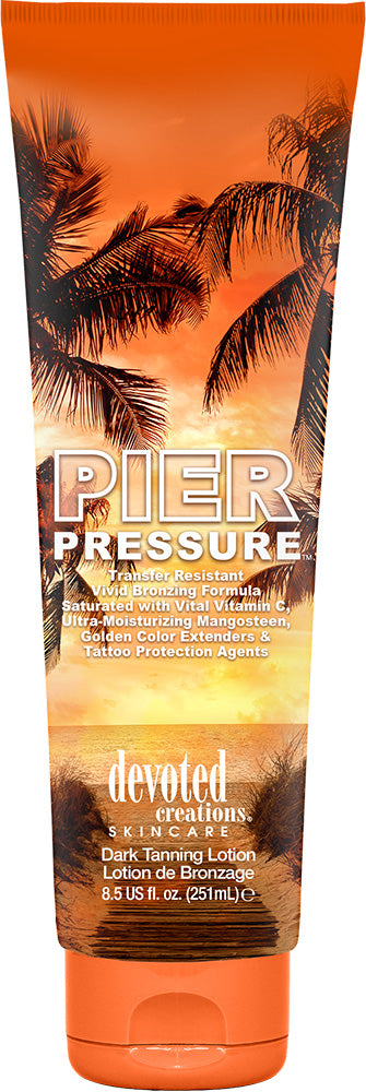 A bottle of Devoted Creations pier pressure tanning lotion featuring an orange sunset background with palm trees and white text 