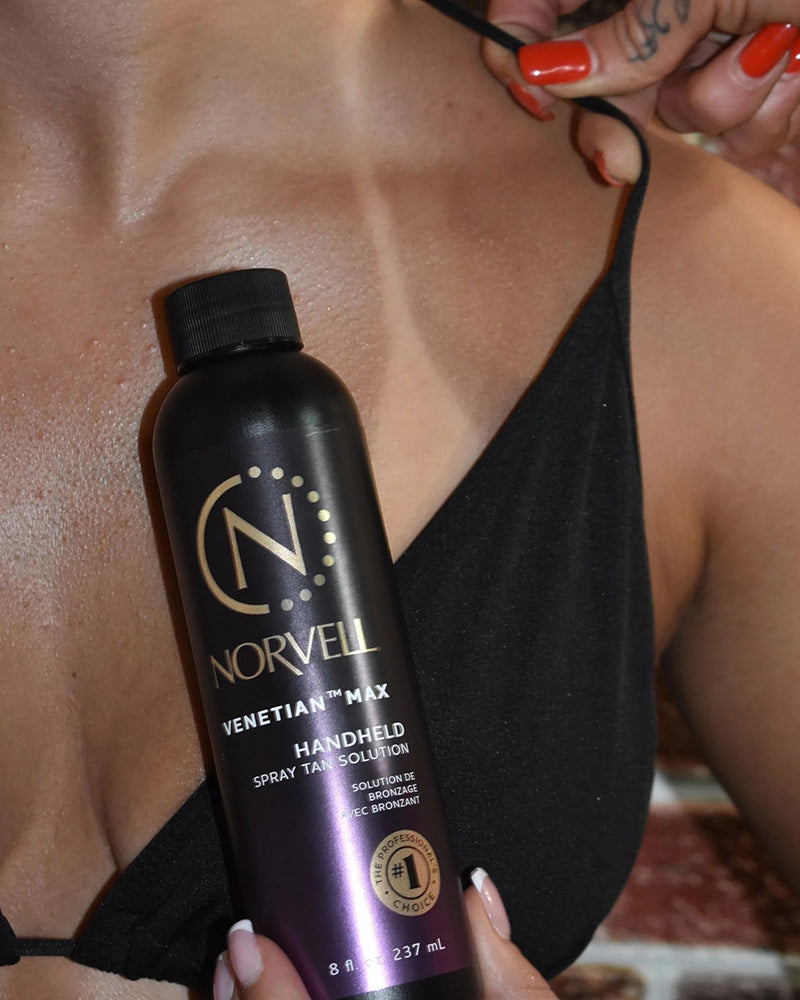 Norvell Venetian Max handheld spray tan solution held by a person wearing a black bikini.