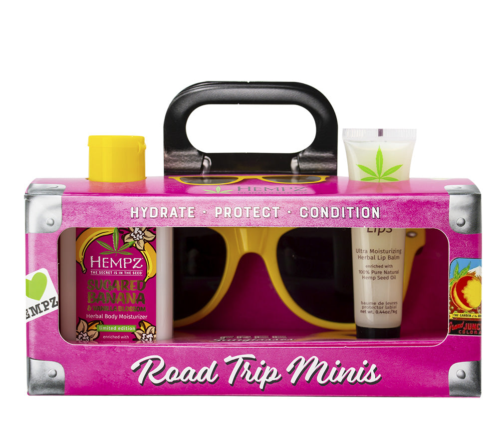Pink 'Road Trip Minis' kit with sunglasses and cosmetic products on a white background