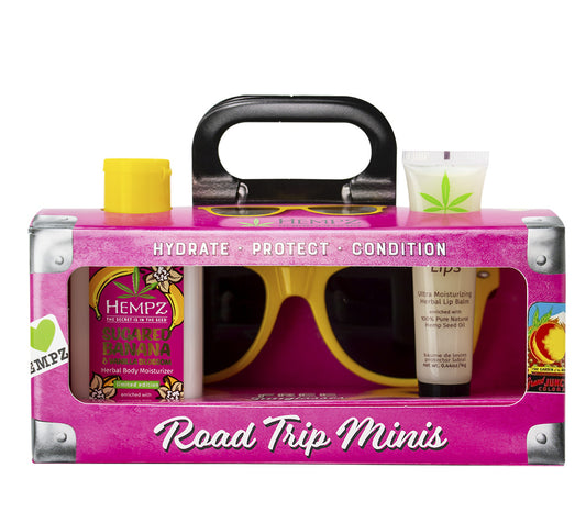 Pink 'Road Trip Minis' kit with sunglasses and cosmetic products on a white background